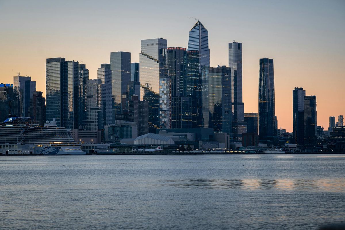 Dense skyline at dusk across open water representing growing organizational scale